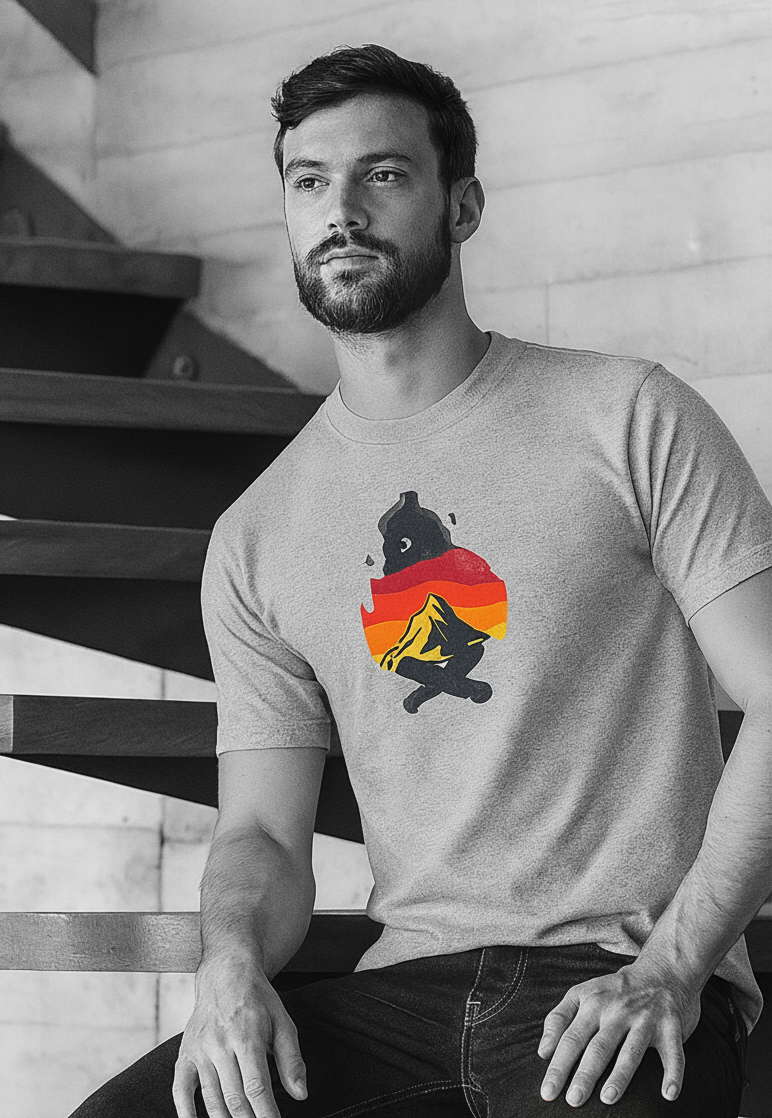 Man wearing a gray t-shirt with a colorful campsite graphic design sitting on a staircase.